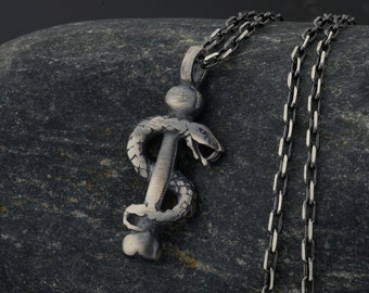 May include: A silver chain necklace with a pendant shaped like a snake wrapped around a staff. The pendant is a medical symbol.
