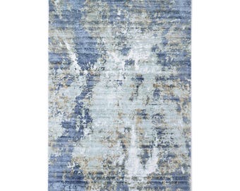May include: Abstract area rug with a blue, white, and beige color scheme. The rug has a distressed, faded look with a subtle horizontal stripe pattern.