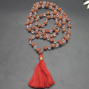 Può includere: Un mala o rosario fatto di quarzo trasparente e perline rudraksha con un fiocco rosso. Il mala è infilato con filo rosso.