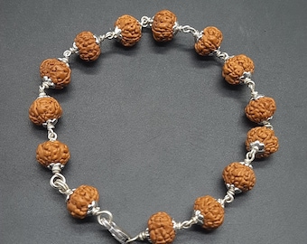 May include: A brown beaded bracelet with silver accents. The beads are round and have a textured surface. The bracelet has a clasp closure.