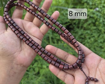 May include: A strand of dark brown cylindrical wooden beads featuring a small dangling section with three additional beads at the end. The beads are uniform in shape and size, with a clearly visible text label indicating 8 mm for the bead diameter.