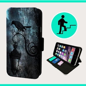 May include: A black phone case with a dark blue and gray design featuring a silhouette of a raven perched on a street lamp. The case is made of leather and has a stand feature.