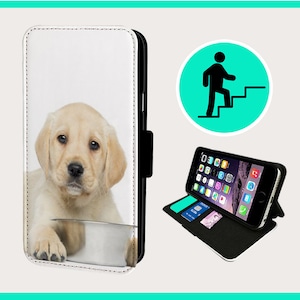 Könnte beinhalten: Eine weiße Leder-Handyhülle mit einem Bild eines Golden Retriever-Welpen. Die Hülle hat eine Klappe, die über den Bildschirm des Telefons klappt, und einen Ständer, mit dem das Telefon aufgestellt werden kann.