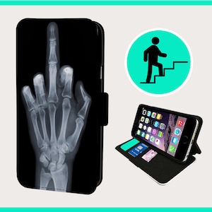 Könnte beinhalten: Schwarze Handyhülle mit einem weißen Röntgenbild eines Mittelfingers auf der Vorderseite. Die Hülle ist geschlossen und das Handy ist nicht sichtbar. Die Hülle hat eine Klappe, die sich über das Handy klappen lässt.