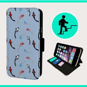 Puede incluir: Una funda de teléfono azul con un patrón de peces koi rojos, blancos y negros. La funda está hecha de cuero y tiene una función de soporte. La funda se muestra con un teléfono en su interior.