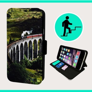 May include: A black leather phone case featuring a colourful image of a train crossing a stone bridge. The case has a stand function and a flap that closes with a magnetic clasp.