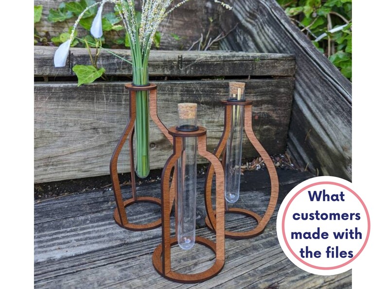 May include: Three wooden test tube holders with glass test tubes inside. The holders are brown and have a rounded shape. The test tubes are clear and are filled with green stems and white flowers.