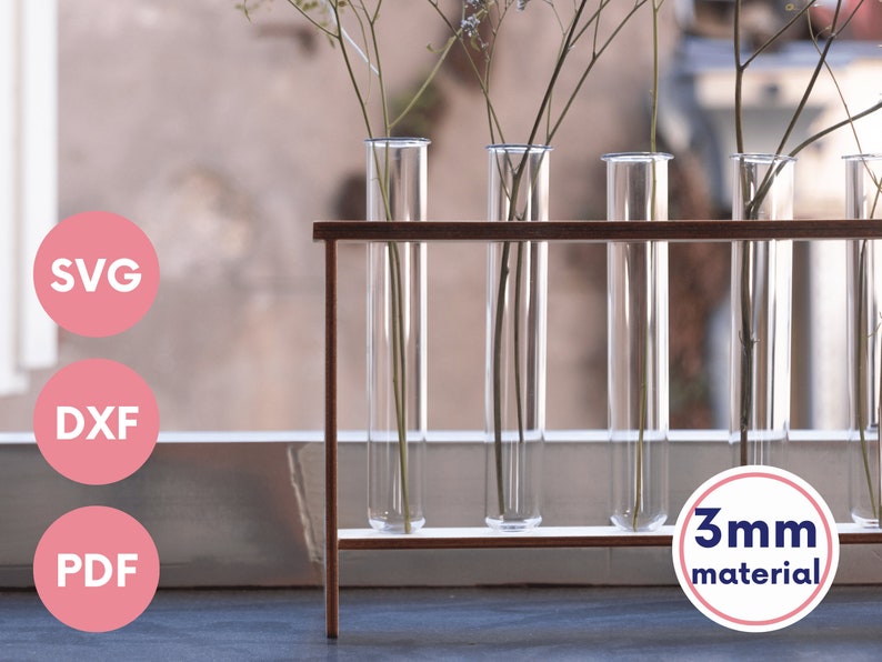 Puede incluir: Un soporte de madera con cinco tubos de ensayo de vidrio transparente, cada uno con una peque&ntilde;a rama de flores secas. El soporte est&aacute; hecho de material de 3 mm. El soporte est&aacute; sobre una superficie marr&oacute;n claro.