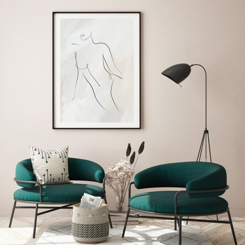 May include: Two teal green armchairs with black metal frames, a black floor lamp, and a framed black and white line drawing of a person on a beige background.