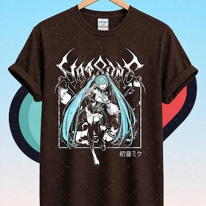 May include: Brown t-shirt featuring a graphic of a female anime character with long, turquoise hair. The design includes the text "Hatsune Miku" in stylized lettering and Japanese characters. The character is set within a white rectangular frame.