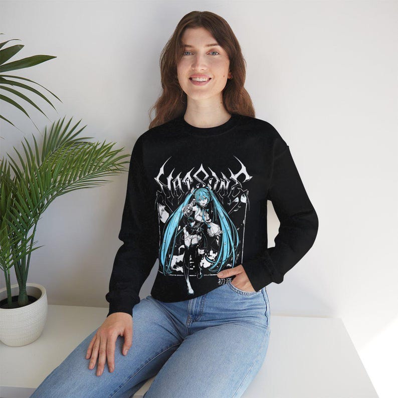 May include: Black long-sleeve sweatshirt featuring a graphic of a female anime character with long blue hair. The graphic is in black and white with the word "Chaosony" in a gothic font above the character. The sweatshirt is worn by a person.