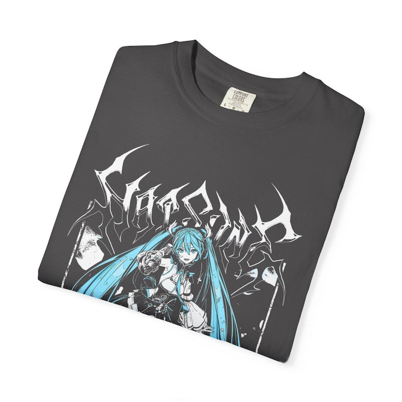 May include: Dark gray t-shirt featuring a graphic of an anime character with long, light blue hair and the word "Hatsune Miku" in stylized white lettering. The shirt is folded and has a tag.
