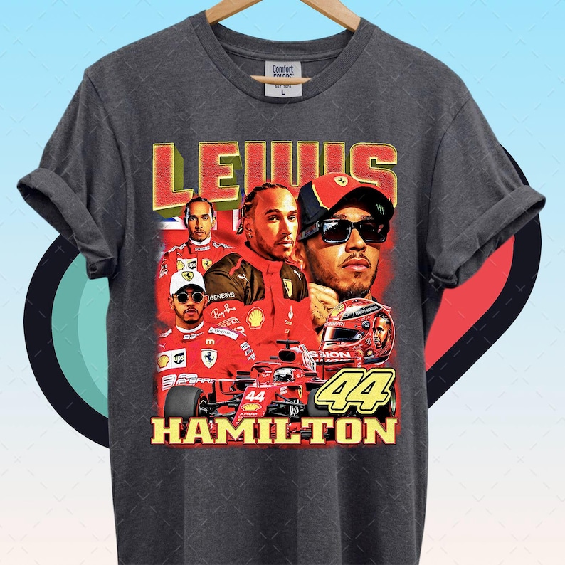 Pode incluir: T-shirt cinzento escuro com um design retro com Lewis Hamilton, um piloto de F&oacute;rmula 1. A camisa exibe o nome "LEWIS HAMILTON" e o n&uacute;mero "44" em um estilo vintage, com imagens do piloto.