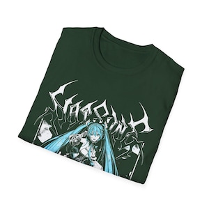 May include: Dark green t-shirt featuring a graphic of an anime character with long, light blue hair. The character is set against a white, stylized text design. The shirt is made of a soft material.