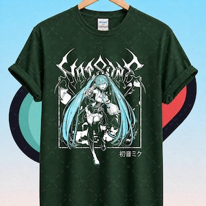 May include: Dark green t-shirt featuring a white graphic of an anime character with long turquoise hair. The graphic includes the text "Star Song" and Japanese characters. The shirt is hanging on a wooden hanger.