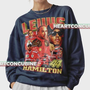 Pode incluir: Camisola azul marinho com um design vintage com imagens de Lewis Hamilton e o texto "LEWIS HAMILTON 44". O design inclui imagens de Hamilton com roupa de corrida e um carro de F&oacute;rmula 1.