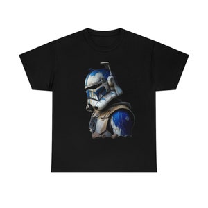 Pode incluir: Uma camiseta preta com uma ilustração branca e azul de um clone trooper de Star Wars. O trooper está usando um capacete e armadura com um esquema de cores azul e branco.