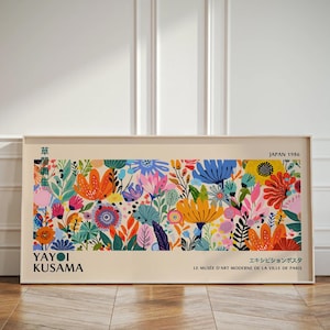 Può includere: Un poster colorato con un design floreale su sfondo bianco. Il poster è incorniciato in una cornice bianca e include il testo "YAYOI KUSAMA" e "JAPAN 1986".