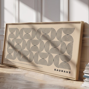 Könnte beinhalten: Ein gerahmter Bauhaus-Kunstdruck mit einem sich wiederholenden Muster aus schwarzen Halbkreisen auf beigem Hintergrund. Der Druck befindet sich in einem hellen Holzrahmen und lehnt an einer weißen Wand. Das Wort "BAUHAUS" ist unten in Schwarz gedruckt.