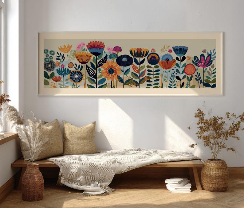 May include: A framed floral art print featuring a colorful array of stylized flowers in shades of orange, blue, pink, and yellow. The artwork is set against a neutral background and framed in a light-colored wood. The print is displayed above a wooden bench with pillows and a blanket.