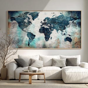 May include: Large framed world map art print. The map features a vintage design with blue and white continents against a neutral background. The frame is a light wood color. The artwork is displayed above a white sectional sofa.