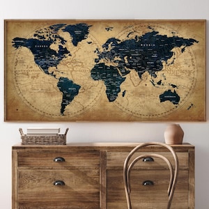 Peut inclure: Une carte du monde encadrée avec une esthétique vintage. La carte présente des continents bleu foncé sur un fond beige. La carte est affichée au-dessus d'une commode en bois.