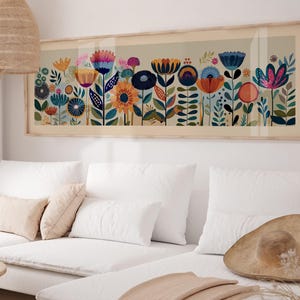 May include: A framed floral art print featuring a colorful array of stylized flowers in shades of blue, orange, pink, and yellow. The artwork is displayed above a white sofa, adding a touch of nature-inspired decor to the room.