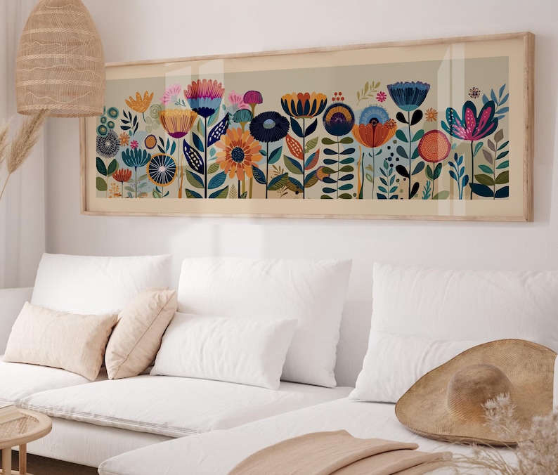 May include: A framed floral art print featuring a colorful array of stylized flowers in shades of blue, orange, pink, and yellow. The artwork is displayed above a white sofa, adding a touch of nature-inspired decor to the room.