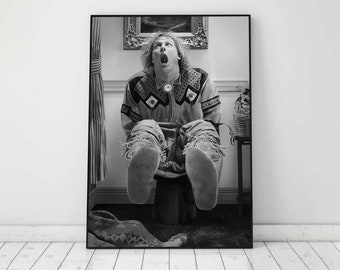 May include: A black and white photograph of a person sitting on a toilet with their legs raised in the air. The person is wearing a patterned shirt and pants. The photo is framed in a black frame.