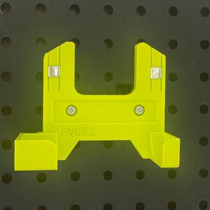 以下が含まれることがあります： 両側に小さな金属片が2つあり、前面に「FVL 52」という文字が印刷された明るい黄色のプラスチック製の壁掛けです。