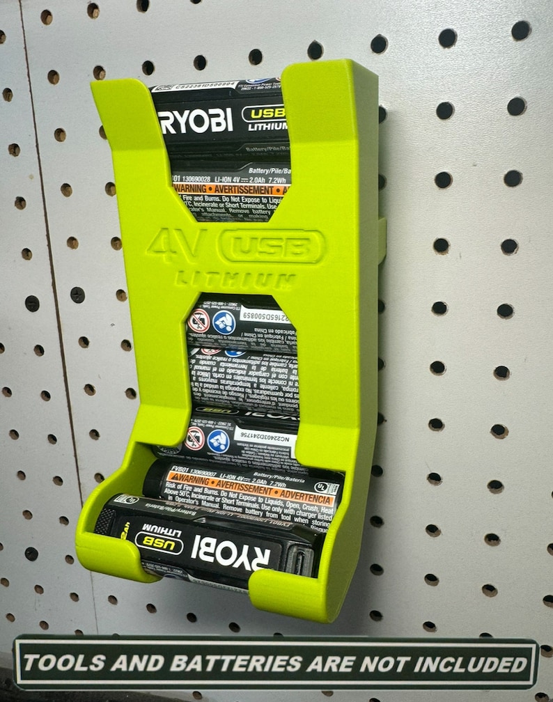 Puede incluir: Un soporte de pared verde para dos bater&iacute;as de iones de litio USB de 4 V. El soporte est&aacute; hecho de pl&aacute;stico y tiene una ranura para cada bater&iacute;a. El soporte est&aacute; etiquetado como "RYOBI USB LITHIUM".