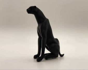 Könnte beinhalten: Eine schwarze Panther-Skulptur in sitzender Position, der Kopf zur Seite gedreht. Die Statue hat eine glatte, matte Oberfläche. Der Panther ist vor einem schlichten Hintergrund platziert. Die Pose deutet auf Wachsamkeit hin.