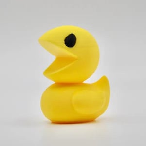 Puede incluir: Un patito de goma amarillo brillante con un diseño de Pac-Man. El pato tiene un cuerpo y una cabeza redondos, con una gran boca abierta y un ojo negro. Un artículo divertido y juguetón.