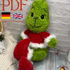 Könnte beinhalten: Ein grüner Plüschcharakter mit einem rot-weißen Outfit. Das Wort "PATTERN PDF" steht oben. Das Bild enthält auch die deutsche und britische Flagge sowie den Text "@Anniis_Plushiees".