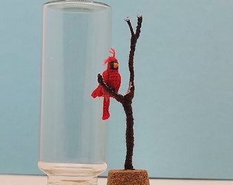Miniatur-Häkelkardinal auf einem Baum, winziger handgefertigter Vogel