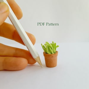 Könnte beinhalten: Eine kleine grüne Topfpflanze mit einem braunen Topf. Die Pflanze ist aus Garn gefertigt und etwa so groß wie ein Bleistift. Der Text "PDF Pattern" ist in Grün über der Pflanze geschrieben.