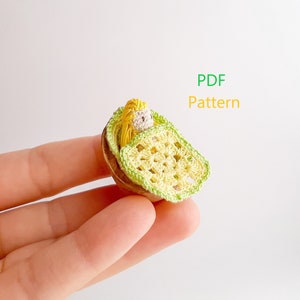 May include: A crocheted doll in a yellow and green cradle, held in a hand. PDF Pattern.
