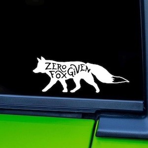 May include: White decal of a fox silhouette with the words "Zero Fox Given" inside the fox's body. The decal is displayed on a black background, with a green surface visible at the bottom.