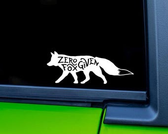May include: White decal of a fox silhouette with the words "Zero Fox Given" inside the fox's body. The decal is displayed on a black background, with a green surface visible at the bottom.