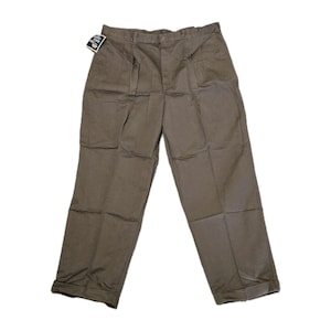 May include: Khaki-coloured pleated trousers with a folded hem. The trousers have a button closure and a tag attached to the waistband. The trousers are made of a durable fabric, suitable for casual or work wear.