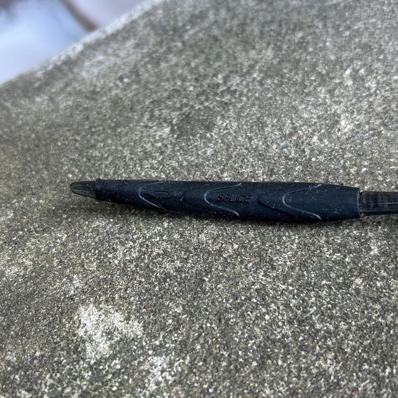 Puede incluir: Un l&aacute;piz &oacute;ptico negro con la palabra "Splice" impresa en el lateral. El l&aacute;piz &oacute;ptico tiene un agarre texturizado para un mejor manejo y una punta para un uso preciso en pantallas t&aacute;ctiles. El l&aacute;piz &oacute;ptico est&aacute; dise&ntilde;ado para dispositivos electr&oacute;nicos.