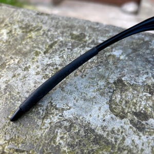 Op de afbeelding: Close-up van een zwarte brilpoot met een rubberen grip. De tekst "MADE IN U.S.A." staat op de poot. De poot is gebogen en loopt taps toe naar een punt.