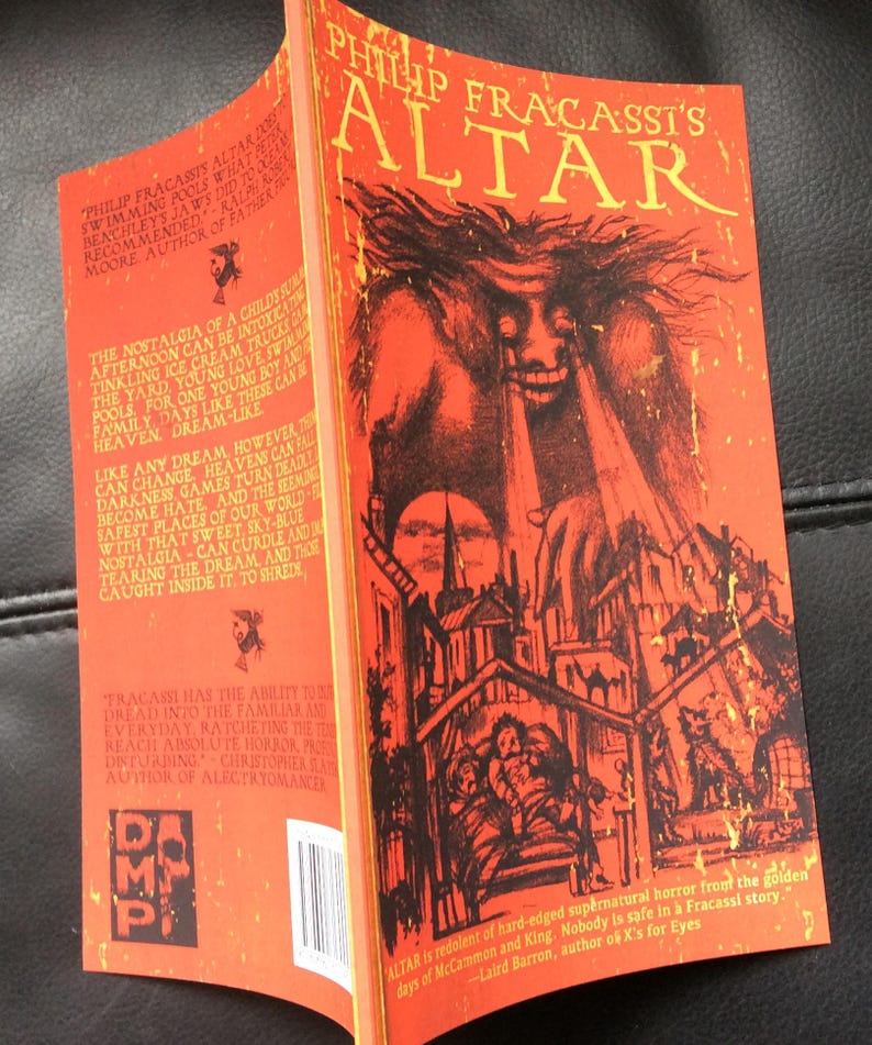 May include: A paperback book titled "Philip Fracassi's Altar" with a red cover featuring a monster illustration. The book's spine is visible, displaying text and a publisher's logo. The cover art depicts a nightmarish scene.
