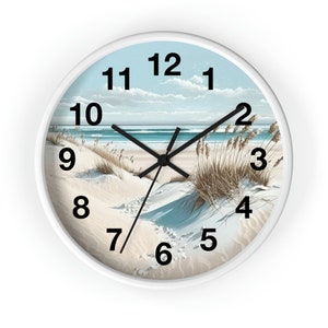 May include: White round clock with black hands and black numbers. The clock face features a beach scene with blue water, white sand, and brown grass.