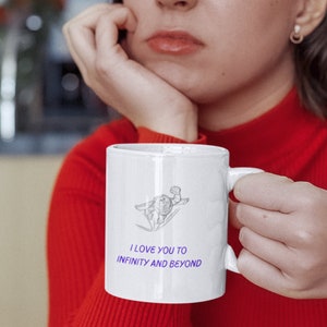 May include: White ceramic mug with a black and white illustration of a character flying through the air. The mug has the text "I love you to infinity and beyond" in purple.
