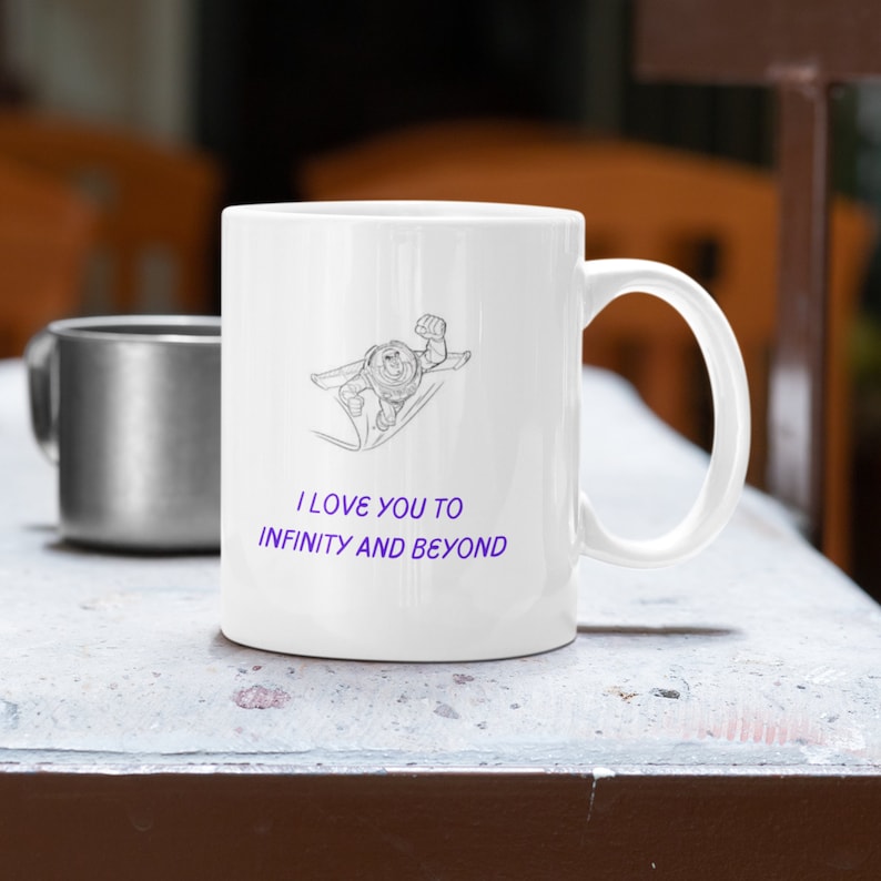 May include: White ceramic mug with a black and white line drawing of Buzz Lightyear from Toy Story. The mug has the text "I love you to infinity and beyond" in purple.