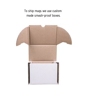 May include: A brown cardboard box with a white interior. The box is open and the top flaps are folded back. The text "To ship mugs we use custom made smash-proof boxes." is printed above the box.