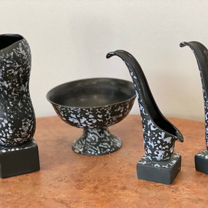 May include: Set of four black and white ceramic vases with a speckled design. The vases are in different shapes and sizes, and they are all on a wooden surface.