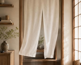 Könnte beinhalten: Ein bodenlanger, cremeweißer Stoffvorhang hängt an einer Holzstange in einem Türrahmen. Der Vorhang ist in der Mitte geteilt und weist eine schlichte, gewebte Textur auf, die Licht durchlässt und für ein weiches, neutrales Erscheinungsbild sorgt.