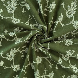 May include: An olive green fabric featuring a delicate white embroidered floral pattern. The design consists of thin, winding branches with small blossoms and leaves scattered across the surface, creating a continuous, intricate botanical motif.